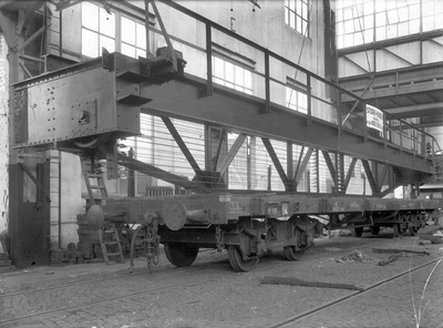 807311 Afbeelding van het plaatsen van een stalen brugdeel op een platte goederenwagen bij de machinefabriek Gebr. ...